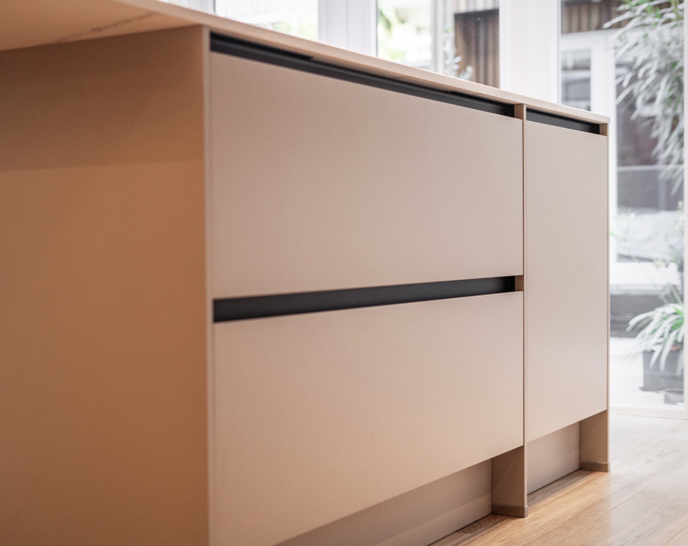 Detail van beige greeploze lades met zwarte greeplijst